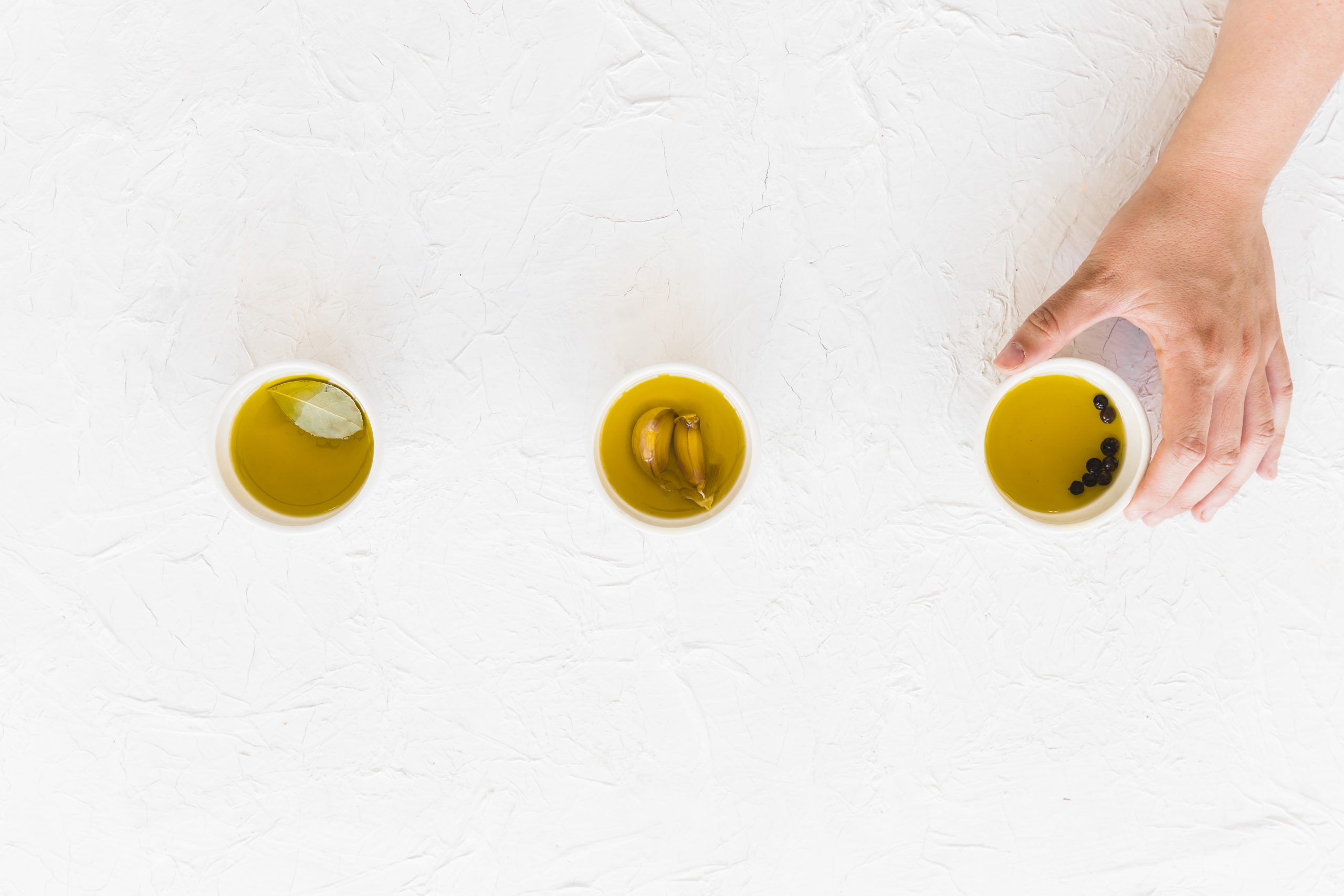 mano-que-sostiene-tazon-fuente-aceite-sobre-fondo-blanco-texturizado